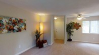 Located at 600 S Churton St in Hillsborough, North Carolina, this single-floor space offers a comfortable and inviting atmosphere with a clean, well-maintained interior design. The layout flows naturally from room to room, creating an open and connected feel throughout.

The main living area is finished with plush carpeting that adds warmth underfoot, while hard surface flooring is visible near the entryway, providing a practical and stylish transition zone. Smooth white walls and standard-height ceilings give the space a bright, airy quality, complemented by warm ambient lighting fixtures that cast a soft glow throughout.

The entryway is clearly defined, framed by a solid interior door and subtle architectural details including a structural column that subtly separates the entry corridor from the main living area. Decorative touches — including colorful wall art, tall floor lamps, and potted plants — add personality and visual interest to the space, suggesting a welcoming and livable environment.

The overall ambiance is calm and neutral, with a palette of soft beiges and whites that provide a versatile backdrop suitable for a variety of interior styles. The single-floor layout ensures ease of movement and accessibility, making the space both functional and comfortable for everyday living.