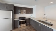 Located at 1110 F Street in San Diego, Unit 502 is a thoughtfully designed single-floor residence that balances modern finishes with a clean, minimalist aesthetic throughout. The open layout, visible in the floor plan, connects the main living area to the kitchen, creating a cohesive flow ideal for everyday living.

The kitchen is a standout feature, outfitted with dark espresso-toned cabinetry, light quartz countertops, and a full suite of stainless steel appliances including a gas range, built-in microwave, and refrigerator. A classic white subway tile backsplash adds a crisp, contemporary touch, while wood-look flooring grounds the space with warmth and durability.

The bedrooms are carpeted in a neutral tone, providing a comfortable and quiet retreat. Each room is finished with crisp white walls and benefits from natural light through windows dressed with horizontal blinds.

The bathrooms are finished with the same attention to detail, featuring quartz-topped vanities with dark wood cabinetry, large framed mirrors with modern sconce lighting, wood-look flooring, and glass-enclosed shower areas. The design maintains a consistent, modern palette throughout.

Overall, the unit presents a clean, contemporary living environment with cohesive finishes and a functional layout suited for urban San Diego living.