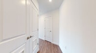 This single-floor residence showcases a clean, contemporary design characterized by crisp white walls, recessed lighting, and warm wood-tone flooring throughout. The open-concept kitchen serves as a central hub, featuring light cabinetry, stainless steel appliances including a refrigerator and microwave, a gas range, and a peninsula with a quartz countertop accommodating two bar-height seats — ideal for casual dining or entertaining.

The living area is bathed in natural light through large, black-framed floor-to-ceiling windows that frame sweeping panoramic views of the surrounding cityscape and skyline, creating a bright and airy atmosphere. Multiple bedrooms continue this theme, each offering generous proportions, wood-tone flooring, and expansive windows with elevated city views. One bedroom includes direct access to an en-suite bathroom.

The bathrooms are finished in a modern style, featuring wood-toned vanities with quartz countertops, undermount sinks, large mirrors, and light tile flooring. The primary bathroom includes a glass-enclosed walk-in shower. A well-proportioned hallway with panel-style doors and louvered storage provides practical connectivity between the living spaces, contributing to the unit's overall clean and functional aesthetic.