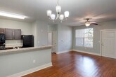 Located at 451 Johns Rd NW in Huntsville, Alabama, this single-floor residence offers a well-designed, open-concept layout ideal for comfortable everyday living. The main living and dining area is finished with rich hardwood flooring that reflects natural light streaming in through a large window. An elegant chandelier anchors the dining space, while a ceiling fan adds functionality to the living area. The kitchen connects seamlessly to this open space via a breakfast bar, and is equipped with dark cabinetry, granite-look countertops, a double stainless steel sink, and black appliances including a refrigerator and range. The bedrooms feature plush carpeting, ceiling fans with light kits, and multiple windows that allow for generous natural light and outdoor views. Each bedroom benefits from direct access to its own private bathroom. The bathrooms are appointed with pedestal sinks, framed mirrors, walk-in showers with built-in shelving and grab bars, and brushed nickel fixtures throughout. The consistent soft gray-green wall palette lends a calm, cohesive ambiance across the entire space, complemented by clean white trim and paneled doors that add a touch of classic detail.