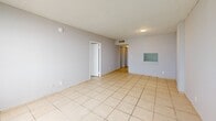 Located at 14795 NE 18th Ave in North Miami, FL, this one-bedroom, one-bathroom unit offers a practical and efficient single-floor layout. Light-toned ceramic tile flooring runs consistently throughout the entire space, creating a clean and cohesive look.

The living room is a bright, open area featuring large multi-pane windows that invite ample natural light and offer views of the surrounding North Miami skyline. The neutral gray walls and textured ceilings complement the airy feel of the room. A pass-through window connects the living area to the kitchen, adding a functional and open design element.

The bedroom is a generously sized private retreat, also benefiting from expansive windows that frame outdoor views. It connects to a spacious walk-in closet equipped with built-in shelving on both sides, providing ample storage and organization options.

The hallways guide the flow of the unit efficiently, leading to a full bathroom outfitted with tile flooring, a tub and shower combination with tiled surround, and classic white fixtures.

The kitchen, accessible via the hallway, completes the layout of this well-organized unit. Overall, the space presents a clean, functional, and straightforward design well-suited to comfortable everyday living in North Miami.
