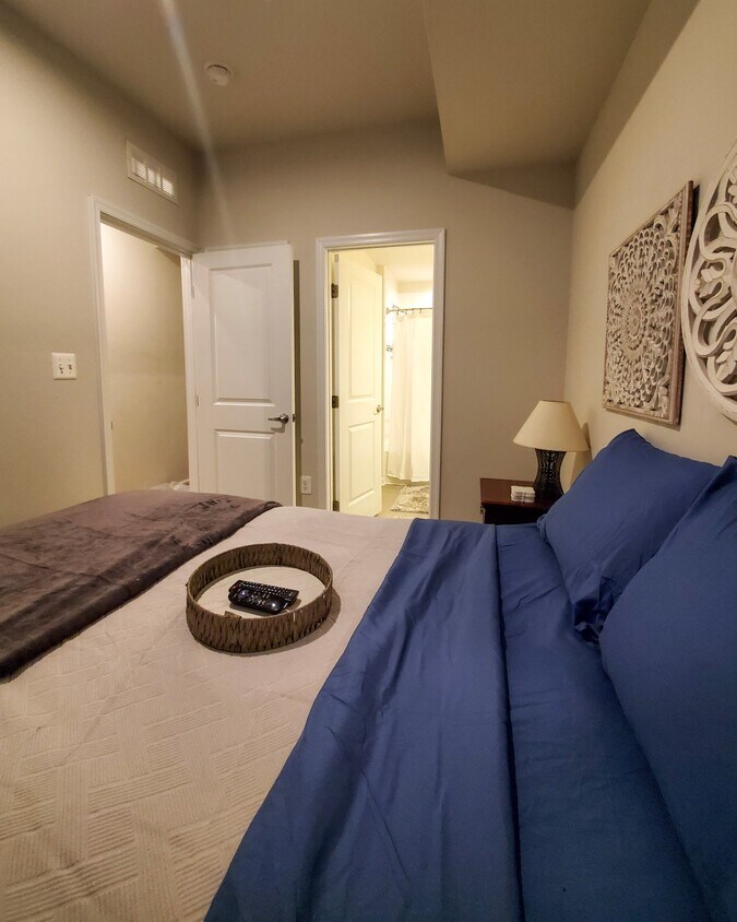 Queen-size bed with remotes and flat screen tv mounted on wall. - 1209 Trenton Pl SE
