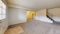 Located at 8 Chapeltowne Cir in Perry Hall, Maryland, this two-bedroom, two-bathroom home is thoughtfully arranged across two floors. The main level features a welcoming living room with soft wall-to-wall carpeting, a front entry door with a large window that allows natural light to fill the space, and a staircase with a black metal railing leading to the upper level. The galley-style kitchen is well-equipped with warm honey-toned wood cabinetry, gray laminate countertops, tile flooring, and white appliances including a refrigerator, electric range, and built-in microwave. Adjacent to the kitchen is a utility area with in-unit washer and dryer hookups, additional cabinetry, and a window overlooking the exterior. Upstairs, two carpeted bedrooms offer comfortable retreats, each with windows providing natural light. The spacious primary bedroom includes a closet and easy access to a full bathroom. The second full bathroom features classic white tile flooring, a wood-toned vanity, and a separate glass-enclosed shower stall. A hallway and closet round out the upper floor, providing practical storage. The home's neutral palette and consistent finishes create a clean, functional living environment throughout.