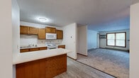 Located at 4605 W Chippewa Cir in Sioux Falls, South Dakota, this single-floor, two-bedroom, two-bathroom home offers a practical and comfortable layout with consistent finishes throughout. The living room serves as a welcoming focal point, highlighted by a classic brick fireplace with a wood mantel, a large window that invites natural light, and plush carpeting underfoot — all topped with a textured ceiling. The kitchen is well-appointed with warm oak cabinetry, ample upper and lower storage, white appliances including a range, microwave, and dishwasher, and light wood-look flooring. A peninsula counter extends the workspace and provides additional seating potential, while an open sightline connects the kitchen to the living area. Both bedrooms feature carpet flooring, natural light from windows with blinds, and access to closet space — the primary bedroom includes a ceiling fan for added comfort. The two bathrooms are clean and functional, each featuring oak vanities with light countertops and tile-style flooring; one includes a full tub-shower combination. With five closets distributed throughout, storage is a notable strength of this home. Baseboard heating is present throughout the space, ensuring efficient warmth.