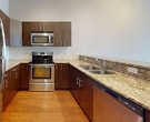 This contemporary 1170 square foot apartment offers a blend of comfort and style. The single bedroom, spanning 160 square feet, provides a cozy retreat with ample natural light from large windows offering urban views. The living space is enhanced by three full bathrooms, ensuring convenience and privacy.

The heart of the home is the open-concept kitchen and living area. The kitchen boasts rich wood cabinetry, gleaming granite countertops, and high-end stainless steel appliances, perfect for culinary enthusiasts. A breakfast bar separates the kitchen from the living area, ideal for casual dining or entertaining.

Throughout the apartment, warm wood flooring adds a touch of elegance and continuity. The living room and bedroom feature expansive windows that flood the spaces with natural light and provide stunning city views. Recessed lighting throughout adds to the modern ambiance.

The bathrooms are sleek and functional, with one showcasing a spacious vanity with ample storage. Neutral color schemes and clean lines maintain the contemporary aesthetic throughout the apartment.

Two hallways contribute to the efficient layout, while a separate dining area offers space for more formal meals. The overall design maximizes the use of space, creating a comfortable and stylish urban dwelling.
