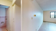 Located on the 6th floor at 735 SW Saint Clair Ave in Portland, Oregon, this one-bedroom, one-bathroom residence offers a practical and well-organized layout. Light wood flooring runs throughout the unit, complementing the warm, neutral wall tones and textured ceilings found in each room.

The combined kitchen and living area forms the heart of the unit. The kitchen features white cabinetry, laminate countertops, a full-size refrigerator, and an electric range, providing functional storage and prep space. The living area is bright and open, with a large window that frames views of the Portland cityscape and surrounding treetops, along with a wall-mounted HVAC unit for year-round climate control.

The bedroom is a well-proportioned, private retreat with its own window offering additional natural light and outdoor views. A set of built-in closet doors provides ample storage. The room's light flooring and neutral palette maintain the cohesive, clean aesthetic carried throughout the unit.

The bathroom includes a full soaking tub with an overhead shower, tiled surround walls in a classic light tone, and chrome grab bar fixtures. Two hallways connect the rooms efficiently, contributing to the unit's straightforward and functional flow. This residence offers a comfortable and understated living environment in the heart of Portland.