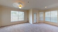 This single-floor residence offers a well-organized layout with distinct living, kitchen, bedroom, and bathroom areas. The living room is a standout space, featuring plush carpeting, crown molding, and a ceiling fan with a light fixture. Multiple windows fitted with horizontal blinds allow generous natural light to fill the room, creating a bright and welcoming atmosphere. A secondary door within the living area provides additional access to the outside.

The kitchen connects to the living area via a pass-through counter, offering an open and functional design. Light wood cabinetry pairs with speckled laminate countertops, while white appliances — including a range, built-in microwave, and refrigerator — provide a cohesive look. Hardwood flooring runs through the kitchen and extends into an adjacent utility or storage area.

The bedroom is a quiet, carpet-floored room with neutral walls and a single window that brings in natural light. The bathroom features a wide vanity with a single sink, speckled countertop, and light wood cabinetry, complemented by a large mirror. Hardwood flooring continues here, and a shower-tub combination with a curtain completes the space. Overall, the unit maintains a clean, neutral palette throughout.