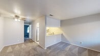 Located at 598 N Walton Ave in Yuba City, California, this single-story, one-bedroom, one-bathroom unit offers a functional and well-organized layout across a compact but efficiently utilized floor plan. The living area features neutral gray walls, plush carpeting, and a pass-through window connecting to the kitchen, allowing natural light to flow between the two spaces. The kitchen is a galley-style design lined with white cabinetry on both sides, offering ample storage and counter space. Light wood-style flooring runs throughout the kitchen, complementing the clean, bright aesthetic created by the white appliances, including a full-size refrigerator and range. The bedroom is carpeted and bathed in natural light through a distinctive arched window that adds an architectural touch to the otherwise understated room. The bathroom is clean and practical, featuring light wood-style flooring, a sliding glass door enclosing a tub and shower combination, a toilet, and a vanity with a wide mirror and wall-mounted lighting above. The overall color palette throughout the unit is soft and neutral, with gray walls and white trim creating a cohesive, move-in-ready atmosphere. The unit provides a straightforward, comfortable living arrangement well-suited for individuals or couples.