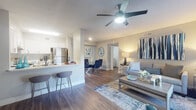 Located at 10474 Boynton Place Circle in Boynton Beach, Florida, this single-floor residence offers a well-designed open-concept layout with cohesive modern finishes throughout. The living and dining areas flow seamlessly together beneath a ceiling fan with integrated lighting, with rich wood-look flooring underfoot and neutral-toned walls that create a bright, welcoming atmosphere. Large windows allow natural light to fill the living space, offering views of the surrounding greenery. The kitchen features white cabinetry, stainless steel appliances including a refrigerator and range, a light-toned countertop, and a peninsula with bar seating — ideal for casual dining or entertaining. The bedroom is generously proportioned, highlighted by a sliding glass door with vertical blinds that opens to an outdoor area, providing both natural light and exterior access. The bathroom is finished with a white vanity, a wide mirror, and wood-look flooring that carries throughout the home for a unified aesthetic. A dedicated in-unit laundry area with full-size washer and dryer and overhead shelving adds everyday convenience. The overall design presents a clean, contemporary style with a coastal-inspired color palette of blues and grays, making this Boynton Beach residence both functional and visually appealing.