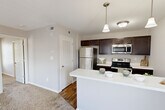 Located at 3405 Hiram St in Saint Charles, MO, this well-appointed one-bedroom, one-bathroom unit offers a thoughtfully designed single-floor layout. The open-concept kitchen is a standout feature, showcasing rich dark-espresso cabinetry, light countertops, and a full suite of stainless steel appliances including a refrigerator, electric range, and over-the-range microwave. A galley-style prep area provides ample counter space, while the wraparound peninsula with pendant lighting creates a natural transition into the living area. Warm hardwood-style flooring runs throughout the kitchen, lending a clean, polished look that contrasts nicely with the plush neutral carpeting found in the living and bedroom areas. The bedroom is a comfortable, quiet retreat featuring a ceiling fan with light fixture, a window with blinds for natural light, and direct access to a closet and the bathroom. The bathroom is clean and functional, with a dark-cabinet vanity, a single-basin sink, and wood-style flooring that ties seamlessly into the rest of the unit. Throughout the space, neutral-toned walls, white trim, and consistent finishes create a cohesive and inviting atmosphere that is both practical and easy to personalize.