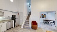 Located at 1000 Navaho Dr in Raleigh, NC, this two-story residence offers a well-organized layout across two floors, combining functional design with a bright, modern aesthetic. Light wood-style flooring and crisp white walls flow throughout, creating a clean and airy atmosphere.

The main floor houses the kitchen, dining room, and living room. The kitchen is outfitted with white shaker cabinetry, granite countertops, stainless steel appliances — including a refrigerator, dishwasher, range, and built-in microwave — and a matte black faucet at the sink. The dining area accommodates a full dining table and is brightened by a window with patterned curtains. The living room impresses with soaring double-height ceilings, a decorative fireplace surround, and natural light from a window, lending a sense of openness well beyond the floor's footprint. A carpeted staircase connects the two levels.

Upstairs, the primary bedroom is a comfortable retreat featuring a closet, a window with natural light, and direct access to a bathroom with a tub-shower combination. A second bathroom serves the home as well. The upper floor's more intimate scale balances the grand volume of the main living area, making this a distinctive and efficiently designed two-story home.