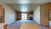 This single-floor unit offers a functional and comfortable layout across several well-defined living areas. The living room is a standout space, featuring vaulted ceilings, plush wall-to-wall carpeting, and a tile-surround fireplace with a classic white mantle. A sliding glass door floods the room with natural light and opens to a private balcony, offering views of the surrounding exterior. A wall-mounted air conditioning unit and baseboard heating ensure year-round comfort.

The kitchen is designed for practicality, featuring warm oak cabinetry with ample upper and lower storage, light countertops, a double-basin stainless steel sink, and a full suite of white appliances including a refrigerator, electric range with over-the-range microwave, and dishwasher. Track lighting overhead adds a functional touch. The kitchen opens directly to the living and dining area, creating an inviting, connected flow.

The bedrooms are generously sized, each fitted with soft carpet, ceiling fans with integrated lighting, baseboard heating, and windows that bring in natural light. One bedroom includes mirrored sliding closet doors, adding depth and storage. The bathroom features tile flooring, a single-basin vanity with oak cabinetry, a stand-up shower, and a linen storage tower, delivering a clean and efficient design.