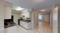 This two-story, 2-bedroom, 1.5-bathroom home offers a well-organized layout across two floors. The main level features light ceramic tile flooring throughout the kitchen, living, and dining areas. The kitchen is equipped with white cabinetry, dark granite countertops, black appliances including a refrigerator, electric range, and dishwasher, and is illuminated by overhead fluorescent lighting. Crown molding accents the kitchen and living areas, adding a touch of detail to the interior. The living area connects seamlessly to the kitchen and features a ceiling fan with light kit, plus access to a rear patio through French doors that bring in natural light. A half bathroom on the main level includes a white vanity with mirror and chrome fixtures. Upstairs, both bedrooms are generously proportioned with plush carpeting, ceiling fans, and windows fitted with blinds for privacy and light control. The primary bedroom includes a walk-in closet. The full bathroom on the upper level features tile flooring, a white vanity, and a full tub-shower combination with chrome hardware. Light-toned walls and textured ceilings are consistent throughout, giving the home a clean, neutral aesthetic well-suited for a variety of furnishing styles.