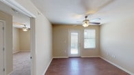 This single-story residence features two bedrooms and two full bathrooms within a well-organized floor plan. The entry hall welcomes residents with wood-look flooring that extends through the main living areas, providing a cohesive and easy-to-maintain surface underfoot. The living area is bright and open, benefiting from natural light admitted through a windowed exterior door that leads to an outdoor space, complemented by a ceiling fan with light fixture overhead and a neighboring window fitted with blinds.

The kitchen is equipped with dark espresso-toned cabinetry, ample upper and lower storage, light-toned countertops, and a full suite of black appliances including a refrigerator, range, and over-the-range microwave. A sink with adjacent counter space adds functional workspace to the room.

Both bedrooms are carpeted for comfort and each features a ceiling fan with lighting and a window with blinds, allowing for natural light and ventilation. The two full bathrooms are finished with tile flooring, dark vanity cabinetry, light countertops, and tub-shower combinations. One bathroom includes a large mirror above the vanity with overhead lighting, while both maintain a clean, neutral aesthetic consistent with the rest of the home.