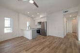 Located at 1450 Cloverfield Blvd in Santa Monica, California, this contemporary single-floor residence showcases a clean, modern design throughout. Light wood-tone flooring runs seamlessly across the entire space, complementing the crisp white walls and lending a bright, airy atmosphere to every room.

The open-concept living and kitchen area serves as the heart of the home. A central kitchen island with a sleek grey finish, undermount sink, and black matte fixtures anchors the space, while stainless steel appliances and recessed lighting add a polished, functional touch. Multiple windows allow abundant natural light to pour in, and a ceiling fan overhead enhances comfort. A glass sliding door opens to a private balcony with wood-deck flooring, offering a pleasant outdoor retreat with neighborhood views.

The bedrooms are generously proportioned with tall ceilings and additional windows that bring in natural light. Built-in closets with sliding doors provide ample storage, while modern flat-panel interior doors with matte black hardware carry the contemporary aesthetic throughout.

The bathroom is thoughtfully designed with hexagonal dark-toned floor tile, a floating grey vanity with a round black-framed mirror, and minimalist fixtures that create a stylish yet functional space. Overall, this residence offers a cohesive, modern living environment in a prime Santa Monica location.