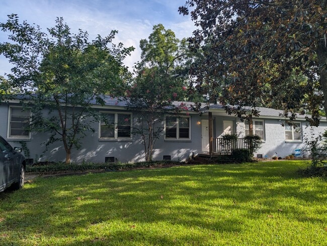Front exterior of the home with green lawn and mature shade trees. - 1527 Brookbank Ave