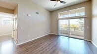 Located at 800 Reliant Way in American Canyon, California, this well-appointed one-bedroom, one-bathroom residence offers a comfortable and modern living experience across a single floor. The open-concept kitchen and living area serves as the heart of the home, where rich dark wood cabinetry, a sleek glass tile backsplash, stainless steel appliances, and light quartz countertops create a stylish and functional space. Warm hardwood-style flooring extends throughout the living area, complemented by a ceiling fan and abundant natural light that pours in through floor-to-ceiling sliding glass doors leading to a private balcony with pleasant outdoor and treetop views. The spacious bedroom features soft wall-to-wall carpeting, a generous sliding-door closet, and a window that frames greenery outside, lending a calm, airy feel. The bathroom is clean and classic, appointed with a full soaking tub and shower combo surrounded by white tile and built-in shelving. A connecting hallway ties the rooms together efficiently, completing the well-organized layout. Neutral tones throughout the unit provide a versatile backdrop, while the overall design balances contemporary style with everyday practicality.