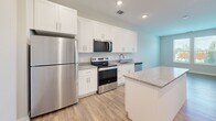 Located at 6045 Bird Key Pl in Palmetto, FL, this single-floor residence offers a thoughtfully designed layout that maximizes both comfort and functionality. Light wood-look flooring runs throughout, complementing the neutral color palette and creating a bright, cohesive atmosphere.

The kitchen is a standout feature, showcasing white shaker-style cabinetry, granite countertops, a central island for additional prep and storage space, and a full suite of stainless steel appliances including a refrigerator, range, microwave, and dishwasher. Recessed lighting illuminates the space efficiently.

The bedroom is a comfortable, well-proportioned retreat with multiple windows fitted with horizontal blinds, allowing for natural light and outdoor views of the surrounding greenery. Ceiling fan connections are in place, and the room connects directly to the rest of the unit through a classic panel door.

The bathroom features a granite-topped vanity with a single undermount sink, a large mirror, and direct access to a dedicated walk-in closet equipped with wire shelving and hanging rods — providing generous storage capacity. The unit's overall design emphasizes clean lines, modern finishes, and practical living in a move-in ready condition.