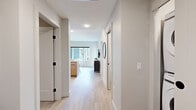 Located at 1946 Ambrosi Rd in Kelowna, BC, this thoughtfully designed one-bedroom, two-bathroom unit offers a well-appointed layout across a single floor. A welcoming entrance leads into a bright, open corridor finished with light hardwood-style flooring and crisp white walls, setting a clean, modern tone throughout.

The kitchen is a standout feature, showcasing two-tone cabinetry in warm wood and soft grey, white subway tile backsplash, stainless steel appliances, and a generous island with a white quartz countertop — ideal for both meal prep and casual dining.

The bedroom is a calm retreat, finished in neutral tones with a window framing views of the surrounding mountains and neighbouring architecture, allowing ample natural light. The walk-through closet connects seamlessly to a well-appointed ensuite bathroom featuring tiled walls, a walk-in shower, and matte black fixtures that add a contemporary edge. A second bathroom with matching black hardware fixtures serves the rest of the unit.

A dedicated office provides a quiet, functional workspace with clean lines and understated finishes. The living area, visible from the 3D overview, offers an open and versatile space ideal for everyday living. Every room reflects a cohesive modern aesthetic, combining practicality with refined design details.