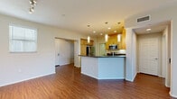 Located at 20455 Sorrento Lane in the Porter Ranch neighborhood of Los Angeles, this two-bedroom, two-bathroom single-floor residence offers a well-organized and functional layout. The open-concept living and kitchen area serves as the heart of the home, featuring warm wood-style flooring, recessed lighting, and a peninsula with dark granite countertops. The kitchen is equipped with light maple cabinetry, stainless steel appliances including a refrigerator, gas range, and microwave, providing ample storage and prep space. Pendant lighting above the peninsula adds a polished finishing touch. The living area extends to a sliding glass door framed by vertical blinds, allowing natural light to fill the space and providing access to an outdoor area. The two bedrooms are carpeted for comfort; the primary bedroom benefits from dual windows with blinds that invite natural light, while the second bedroom includes a built-in closet with sliding doors. Both bathrooms are clean and functional, with one featuring a tub-shower combination enclosed by sliding glass doors and wood-style flooring. A dedicated in-unit laundry room with full-size washer and dryer adds everyday convenience. A hallway connects all areas of the home in a cohesive, efficient floor plan.