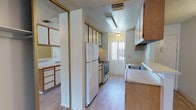 This single-story unit at 43240 16th St W in Lancaster, California offers a straightforward, functional layout designed for comfortable everyday living. The space transitions between light wood-style laminate flooring in the kitchen and entry areas and neutral carpet throughout the living and bedroom spaces, creating a clear delineation between zones.

The galley-style kitchen is well-equipped, featuring warm oak-toned cabinetry that extends to the ceiling for generous storage, a gas range, white refrigerator, and a built-in sink with a window that allows natural light to filter in. A peninsula counter with additional cabinetry opens toward the main living area, providing both a casual workspace and a visual connection between the kitchen and the rest of the unit.

The living area is spacious and open, with a textured ceiling, neutral walls, and a sliding glass door that leads to an outdoor area. Bedrooms are carpeted and offer ample wall space, with one featuring a mirrored sliding-door closet framed in gold-toned trim. The bathroom includes a full-size soaking tub with an overhead shower, chrome fixtures, and clean white surround. Throughout, the unit maintains a neutral, move-in-ready aesthetic.
