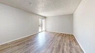Located at 1311 Louisiana Blvd NE in Albuquerque, New Mexico, this single-floor, 2-bedroom, 1-bathroom home offers a straightforward and functional layout. The combined living and dining area is a bright, open space featuring wood-look vinyl flooring, neutral gray walls, and a textured ceiling. A sliding glass door fills the room with natural light and provides direct access to a private patio. The galley-style kitchen runs along one wall and is equipped with white cabinetry, warm wood-toned countertops, a double stainless steel sink, and stainless steel refrigerator alongside a white range, all set atop matching wood-look flooring. The primary bedroom is a comfortable, well-proportioned room featuring a sliding closet and wood-look flooring, while the second bedroom is carpeted and includes a window with natural light. Both bedrooms connect through a hallway with additional closet storage. The bathroom features wood-look flooring, a clean white tub-shower combination, and a toilet. With three closets throughout, the home provides ample storage. The consistent neutral palette and durable flooring choices give the space a clean, move-in-ready feel throughout.
