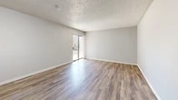 Located at 1311 Louisiana Blvd NE in Albuquerque, New Mexico, this single-floor, 2-bedroom, 1-bathroom home offers a straightforward and functional layout. The combined living and dining area is a bright, open space featuring wood-look vinyl flooring, neutral gray walls, and a textured ceiling. A sliding glass door fills the room with natural light and provides direct access to a private patio. The galley-style kitchen runs along one wall and is equipped with white cabinetry, warm wood-toned countertops, a double stainless steel sink, and stainless steel refrigerator alongside a white range, all set atop matching wood-look flooring. The primary bedroom is a comfortable, well-proportioned room featuring a sliding closet and wood-look flooring, while the second bedroom is carpeted and includes a window with natural light. Both bedrooms connect through a hallway with additional closet storage. The bathroom features wood-look flooring, a clean white tub-shower combination, and a toilet. With three closets throughout, the home provides ample storage. The consistent neutral palette and durable flooring choices give the space a clean, move-in-ready feel throughout.