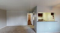 This single-story classic unit in Houston, TX offers a well-organized layout designed for comfortable everyday living. The living room is a generous, open space finished with neutral carpet and gray walls, illuminated by a ceiling fan with a light fixture. A pass-through counter connects the living area to the kitchen, offering a sense of openness between the two spaces. A window in the living room allows natural light to filter in, providing views of the surrounding greenery.

The galley-style kitchen is efficiently designed with dark espresso cabinetry lining both walls, granite-style countertops, a double stainless steel sink, a gas range, and a full-size refrigerator. Wood-style flooring runs throughout the kitchen, adding warmth and durability to the space.

The bedroom features rich, dark hardwood-style flooring, a ceiling fan, a window for natural light, and a closet with built-in shelving for ample storage. An additional smaller room off the bedroom provides further flexibility.

The bathroom includes a full tub-shower combination, a vanity with granite-style countertops, and classic tile flooring, maintaining a clean and functional aesthetic throughout.