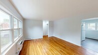 Located at 1614 Monmouth Ave in Lakewood, NJ, this two-bedroom, one-bathroom residence offers a clean and functional single-floor layout. Gleaming hardwood floors flow throughout the living areas and bedrooms, lending warmth and continuity to the space. The living room is generously proportioned, bathed in natural light from large windows that frame outdoor greenery, and features baseboard heating and a wall AC unit for year-round comfort.

The kitchen is well-appointed with crisp white shaker cabinetry, granite-style countertops, a gas range, and a stainless sink. A convenient stacked washer and dryer unit is integrated directly into the kitchen area, adding everyday practicality. Natural light pours in through dual windows and a glass-paneled exterior door, creating an open, airy feel.

Both bedrooms carry the same warm hardwood flooring, neutral walls, and ample natural light. The primary bedroom offers a comfortable footprint with a dedicated closet. The bathroom features clean white tile surrounding a full tub-shower combination, a toilet, and a frosted window for privacy. The overall aesthetic is bright, neutral, and move-in ready, making this a practical and inviting residence.