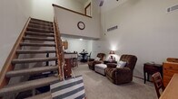 Located at 3900 Wyndover Dr in Springfield, Ohio, this two-story home is defined by its striking double-height living room, where soaring ceilings and an open upper loft area create a grand sense of vertical space. A wooden staircase with warm-toned balusters ascends from the main level, serving as a functional architectural centerpiece. The living area is carpeted and offers generous room for seating, with a convenient under-stair nook that adds practical storage or display space.

Adjacent to the living room, a dedicated dining area features wood-look flooring and connects to the galley-style kitchen. The kitchen is well-appointed with warm wood cabinetry, granite-look countertops, a double sink, gas range, and full-size refrigerator, offering ample storage and workspace.

Two bathrooms serve the home, each featuring wood vanities with granite-look counters and wood-look flooring. One includes a shower-tub combination. The bedrooms are carpeted and comfortable in scale, with ceiling fans providing airflow. One bedroom has direct access to a bathroom, enhancing functionality. Throughout, the home maintains a neutral palette with warm wood accents, creating a cohesive and welcoming atmosphere across both floors.