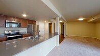 Located at 10500 NE 51st Cir in Vancouver, Washington, this single-floor residence offers a well-designed, open layout with a thoughtful mix of flooring and finishes throughout. The kitchen serves as a central hub of the home, featuring rich wood cabinetry, dark laminate countertops, a stainless steel refrigerator, a built-in dishwasher, and a double sink integrated into a peninsula that opens directly to the living area. Warm hardwood-style flooring runs through the kitchen and extends into the entryway and bathrooms, adding a cohesive and durable touch.

The spacious living area is carpeted and filled with natural light from multiple windows fitted with vertical blinds, and a sliding door provides direct access to an outdoor balcony with exterior views. A wide hallway connects the living spaces to the bedrooms, each of which is carpeted and offers generous proportions.

The unit includes two bathrooms. One features a soaking tub with shower combination and hardwood-style flooring. The second is a larger, accessibility-equipped bathroom with multiple grab bars, a wide vanity with a large mirror, warm wood cabinetry, and hardwood-style flooring. Throughout, the warm neutral wall tones and clean white trim create a bright, welcoming atmosphere.
