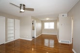 This single-floor residence offers a clean, functional layout with warm, polished hardwood flooring that runs throughout the main living and bedroom areas, lending a cohesive and inviting character to the space. Neutral gray walls provide a versatile backdrop throughout, complementing the bright white trim and baseboards.

The main living area is generously proportioned, featuring a ceiling fan with integrated lighting and built-in shelving that adds both storage and visual interest. A second bedroom is equally well-sized, also equipped with a ceiling fan, and benefits from a wide bank of windows that invite natural light. Multiple bedrooms are present, each finished with the same warm hardwood floors and outfitted with dedicated closet space — some rooms offering two closets for added storage capacity.

The kitchen is efficiently designed in a galley-style configuration, featuring white cabinetry, dark granite-look countertops, a double stainless steel sink, and wood-look tile flooring. A white electric range, refrigerator, and a window providing natural light complete the space.

The bathroom is bright and clean, finished in white throughout, with a single-vanity sink, a full bathtub and shower combination, and a frosted window that allows natural light while maintaining privacy. The overall ambiance of this residence is practical, well-maintained, and move-in ready.