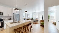 Located in West Jordan, Utah, this single-floor residence offers a thoughtfully designed open-concept layout with a clean, contemporary aesthetic. Light wood flooring flows seamlessly throughout, complementing the bright white walls and creating a warm, cohesive atmosphere.

The kitchen is well-appointed with white shaker cabinetry, stainless steel appliances, a subway tile backsplash, and a light wood island with bar seating and pendant lighting overhead — ideal for both casual dining and entertaining. The kitchen opens directly into the living area, which features large windows with blinds, a ceiling fan, and a private exterior door that fills the space with natural light.

The primary bedroom is generously proportioned with ample wall space and access to a private bathroom. The en suite bathroom features a white vanity with quartz countertops, modern fixtures, and direct access to a spacious walk-in closet with wire shelving and hanging storage on multiple walls. A second bedroom offers a clean, versatile space with the same wood flooring and neutral palette. A second bathroom mirrors the refined finish of the primary bath, with a white vanity, quartz countertop, and large mirror. The overall design balances modern functionality with a light, airy ambiance throughout.