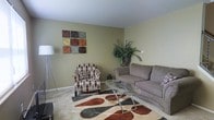 Located at 670 Partridge Road in Heath, Ohio, this two-story home offers a thoughtfully arranged layout across two floors, providing ample space for everyday living. The living room sets a welcoming tone with its neutral, earth-toned walls that create a warm and relaxed atmosphere. Plush carpeting underfoot adds comfort, while a boldly patterned area rug anchors the seating arrangement and introduces a pop of color to the space. The room is furnished with a generously sized sofa and a coordinating accent chair, centered around a sleek glass-top coffee table that adds a contemporary touch. Decorative wall art and lush indoor greenery contribute to the inviting ambiance, reflecting a thoughtful approach to interior styling. Natural light filters into the room, enhancing the open and airy feel. The two-floor configuration of the home allows for a natural separation between living and private spaces, making it well-suited for a variety of lifestyles. The overall design aesthetic balances comfort and functionality, with warm tones and carefully chosen furnishings that create a cohesive and livable environment throughout this Heath, Ohio residence.