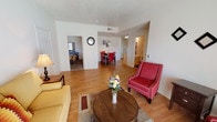 Located at 2600 Americare Ct NW in Albuquerque, New Mexico, this single-floor unit offers a functional and well-organized layout throughout. The living area features wood-style laminate flooring that extends through the main living spaces, filling the room with a clean, cohesive aesthetic. A large sliding glass door allows natural light to pour in and provides direct outdoor access, while a front window adds additional brightness to the space. Textured ceilings are consistent throughout the unit.

The open layout connects the living area to the dining space and kitchen, which is designed as a galley-style corridor with light wood cabinetry lining both sides. The kitchen is equipped with a white electric range, refrigerator, dishwasher, and a double-basin sink, along with ample counter space and a dedicated pantry or storage closet at the end of the kitchen. A pendant light fixture highlights the dining area just off the kitchen pass-through.

The bedrooms are carpeted for comfort and feature natural light from windows with blinds. Closet space is available within the bedroom areas. The bathroom includes a full tub-and-shower combination with chrome fixtures, a toilet, and a vanity sink, all finished in neutral tones. The unit's straightforward design and practical layout make it a functional living space in a convenient Albuquerque location.