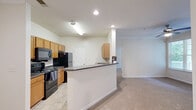 Located at 7075 Walton Reserve Ln in Austell, Georgia, this single-floor residence offers a well-organized layout with two bedrooms, two full bathrooms, and a thoughtfully arranged set of living spaces. The kitchen is equipped with warm honey-toned wood cabinetry, dark granite-style countertops, a subway tile backsplash, black appliances including a gas range, built-in microwave, refrigerator, and dishwasher, plus a peninsula breakfast bar that connects seamlessly to the living area. Tile flooring runs through the kitchen and bathrooms, while plush carpet extends throughout the living spaces and bedrooms. Both bedrooms are comfortably sized, featuring ceiling fans, natural light from double windows with views of surrounding greenery, and access to closets with built-in shelving. The primary bedroom offers a notably generous footprint with an en-suite closet. Each bathroom includes a full tub-shower combination with white tile surround, dark countertops, and stone-look tile flooring. A dedicated hallway connects the bedrooms and provides access to additional closets. The laundry room is equipped with washer and dryer hookups, overhead wire shelving, and utility connections, adding everyday convenience to this functional and comfortable home.