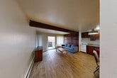 Located at 832 Packard St in Ann Arbor, Michigan, this one-bedroom, one-bathroom unit offers a well-organized and functional layout across a single floor. Wood-look plank flooring runs throughout, lending warmth and visual continuity to the space, while distinctive exposed dark wood beams add architectural character overhead.

The open living room serves as the heart of the unit, anchored by a striking floor-to-ceiling wood-paneled accent wall fitted with built-in shelving — an ideal display and storage feature. A sliding glass door fills the room with natural light and opens directly onto a private balcony, offering outdoor access and pleasant views of the surrounding neighborhood.

The kitchen and dining area flow together seamlessly, featuring rich dark wood cabinetry, granite-look countertops, a stainless steel sink, and full appliances including a refrigerator and range. The space is compact yet highly functional.

The bedroom is a comfortable retreat with its own exposed beam detail, a large built-in wood closet, a window with vertical blinds, and additional storage. Two closets throughout the unit provide ample organization options.

The bathroom includes a full tub-shower combination with tiled surround and a decorative mosaic accent border. A hallway connects all areas, completing this efficiently designed Ann Arbor residence.