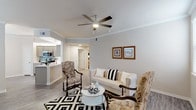 This single-floor residence offers a thoughtfully designed layout that balances comfort and functionality throughout. The living room serves as the heart of the home, featuring crown molding, wood-look flooring, a ceiling fan, and ample natural light streaming in through multiple windows. The open-concept design allows for a seamless flow between the living area and the kitchen, which is equipped with stainless steel appliances including a range and over-the-range microwave, sleek gray cabinetry, white quartz countertops, a stainless steel sink, and a teal accent backsplash that adds a pop of color. The bedrooms are generously sized, each with plush carpeting, ceiling fans, and large windows that bring in natural light. One bedroom features a charming bay window configuration, while another opens through an elegant arched passage. Both bathrooms are finished with gray wood-look vinyl flooring, modern vanities with white countertops, and tub-shower combinations. A dedicated in-unit laundry room with full-size washer and dryer hookups and overhead shelving adds everyday convenience. The overall ambiance is light, neutral, and move-in ready.