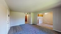 Located at 1101 E Lassen Ave in Chico, California, this two-bedroom, one-bathroom unit offers a practical and comfortable single-floor layout. The living room is a generous, open space featuring plush blue-gray carpeting and light-toned walls, with a transition to luxury vinyl plank flooring near the entryway. A six-panel front door welcomes residents into this well-organized space. The kitchen is efficiently designed in a galley-style configuration, featuring warm wood-toned cabinetry, light countertops, a double stainless steel sink, an electric range, a dishwasher, and a refrigerator. A peninsula counter opens toward the dining and living areas, enhancing the sense of connectivity between spaces, while a ceiling fan provides added comfort overhead. Both bedrooms are carpeted and benefit from natural light through sliding windows that frame pleasant views of surrounding greenery. The primary bedroom offers a comfortable footprint with ample space for furnishings. The full bathroom includes a single-sink vanity with wood cabinetry, a tub-shower combination, and LVP flooring. Two closets provide dedicated storage throughout the unit. The overall ambiance is clean, neutral, and move-in ready.