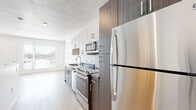 Located at 30 N Orange St in Salt Lake City, Utah, this contemporary single-floor unit offers a well-designed layout with modern finishes throughout. The kitchen is a standout feature, showcasing a thoughtful combination of white upper cabinetry and dark wood-toned lower cabinets, complemented by dark countertops and a full suite of stainless steel appliances including a refrigerator, electric range, built-in microwave, and dishwasher. A window at the end of the kitchen allows natural light to fill the space. Light wood-style flooring runs consistently throughout the unit, creating a warm, cohesive aesthetic that pairs well with the crisp white walls. The living area is bright and open, with a large window offering outdoor views and ample natural light. A dedicated in-unit laundry area with a stacked washer and dryer adds everyday convenience, situated alongside a spacious closet. The bathroom features warm wood-tone cabinetry with a dark countertop vanity, a large mirror, and a full tub-shower combination, all finished with clean white walls and matching wood-style flooring. The overall design reflects a clean, modern sensibility well-suited to contemporary urban living in Salt Lake City.