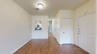This two-floor residence offers a clean, functional layout with a consistent design aesthetic throughout. The main level features durable wood-look flooring that extends across the open living area, which is brightened by natural light from front-facing windows and equipped with a ceiling fan. A pass-through window connects the living space to the kitchen, which is outfitted with white shaker-style cabinetry, dark granite-style countertops, and black appliances including a range, microwave, and dishwasher. A bathroom on the main level features a white vanity with dark countertop, a large mirror, and hardwood-style flooring. Carpeted stairs lead to the upper floor, where the bedrooms offer plush carpet flooring, ceiling fans, and windows that allow natural light to filter in. The rooms are finished with neutral tones throughout, creating a bright and airy atmosphere. White panel doors, clean baseboards, and textured ceilings are consistent design elements found across both floors. The overall layout is straightforward and well-organized, providing a comfortable and livable environment suited to a variety of needs.