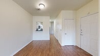 This two-floor residence offers a clean, functional layout with a consistent design aesthetic throughout. The main level features durable wood-look flooring that extends across the open living area, which is brightened by natural light from front-facing windows and equipped with a ceiling fan. A pass-through window connects the living space to the kitchen, which is outfitted with white shaker-style cabinetry, dark granite-style countertops, and black appliances including a range, microwave, and dishwasher. A bathroom on the main level features a white vanity with dark countertop, a large mirror, and hardwood-style flooring. Carpeted stairs lead to the upper floor, where the bedrooms offer plush carpet flooring, ceiling fans, and windows that allow natural light to filter in. The rooms are finished with neutral tones throughout, creating a bright and airy atmosphere. White panel doors, clean baseboards, and textured ceilings are consistent design elements found across both floors. The overall layout is straightforward and well-organized, providing a comfortable and livable environment suited to a variety of needs.