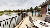 This single-floor space offers a seamless connection between indoor comfort and outdoor living. The standout feature is the expansive outdoor patio, enclosed by sleek black metal railings and designed for relaxed entertaining. Patio seating, including cushioned chairs and a tiled table, is positioned to take full advantage of the remarkable surroundings.

The patio overlooks a picturesque pond complete with an active water fountain, creating a calming ambiance enhanced by the sound of flowing water. Adjacent to the pond, a community swimming pool with a surrounding deck and covered pavilion structure provides additional recreational amenities. Mature trees frame the entire backdrop, offering lush greenery and a sense of privacy.

The outdoor space is finished with a smooth concrete surface, providing a clean and durable foundation suited for year-round use. Decorative planters with vibrant red flowers add a welcoming touch of color to the patio area. The overall atmosphere is peaceful and resort-like, with natural views in every direction. This space is well-suited for those who value outdoor living, scenic water views, and access to community amenities in a well-maintained, landscaped setting.