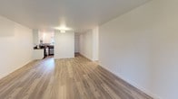 This thoughtfully updated single-floor residence offers a clean, modern aesthetic carried consistently throughout every room. Light-toned hardwood-style flooring flows seamlessly across the entire space, creating a cohesive and airy feel. The open living area is generously proportioned, bathed in natural light from large sliding windows that frame lush outdoor greenery, and is accented by a ceiling-mounted light fixture and a wall-mounted air conditioning unit for year-round comfort.

The kitchen is well-equipped and functional, featuring white shaker cabinetry, dark countertops, a stainless steel refrigerator, dishwasher, and range, all illuminated by track lighting above. A window above the sink brings in natural light, and a stacked washer and dryer unit is conveniently integrated into the kitchen area, adding practical in-unit laundry.

The bedrooms are bright and comfortable, each with ceiling fans, large windows overlooking greenery or the surrounding landscape, and ample natural light. One bedroom includes a sliding-door closet with a full-width hanging rod, providing solid storage capacity. The bathroom features a shower-tub combination with a decorative curtain and clean white fixtures. Throughout, crisp white walls and neutral tones create a calm, move-in-ready environment.