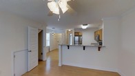 Located at 5020 Garrett Rd in Durham, North Carolina, this two-floor residence offers a well-designed, open-concept living space that balances functionality with comfort. The main living area features warm hardwood-style flooring that flows throughout, creating a cohesive and inviting atmosphere. A ceiling fan with integrated lighting anchors the living space, providing both comfort and illumination.

The kitchen is a standout feature, equipped with stainless steel appliances including a refrigerator and microwave, medium-toned wood cabinetry, and granite-style countertops. A peninsula-style breakfast bar with seating extends into the living area, making it ideal for casual dining or entertaining. The open sightlines between the kitchen and living room enhance the sense of space and connectivity throughout the main floor.

Natural light filters in through windows, brightening the interior and adding to the airy feel of the space. Pendant lighting above the dining area adds a decorative touch, while flush-mount ceiling fixtures provide consistent overhead lighting throughout. The textured ceiling and clean white walls provide a neutral backdrop that complements the warm tones of the flooring and cabinetry. With two floors, the layout offers ample room for living, dining, and private retreats.