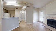 Located in Cedar Park, TX, this one-bedroom, one-bathroom unit offers a well-organized layout across a single floor. The living room is a standout space, featuring light wood-style flooring, a tile-surround fireplace with a white mantle, and multiple windows fitted with blinds that allow natural light to fill the room. A glass-paned door leads to a private balcony overlooking mature trees and lush greenery, offering a peaceful outdoor retreat.

The kitchen is positioned adjacent to the living area and separated by a half-wall breakfast bar. It is equipped with gray-toned cabinetry, light countertops, and a full suite of white appliances including a refrigerator, electric range, built-in microwave, and dishwasher. Light tile flooring runs throughout the kitchen, providing a clean and practical surface.

The bedroom offers comfortable carpeted flooring and a large window with tree views, creating a bright and serene environment. A dedicated walk-in closet with built-in shelving and hanging rods provides ample storage.

The bathroom features tile flooring, a gray vanity with a single sink, a lighted mirror, and a full soaking tub. A hallway connects the main living areas, completing this efficiently designed and move-in ready home.