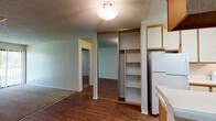 This single-story residence at 43340 16th St W in Lancaster, CA offers a practical and straightforward layout across several distinct areas. The galley-style kitchen is lined with wood-trimmed cabinetry on both sides, providing ample upper and lower storage. White appliances, including a refrigerator and gas range, are paired with a stainless steel sink and laminate countertops. Wood-look flooring runs throughout the kitchen, extending into the adjacent dining and entry areas.

The living area transitions between wood-look flooring and carpeting, creating a natural separation of zones. A sliding glass door fitted with vertical blinds fills the space with natural light and offers a view of the outdoor greenery beyond. A textured popcorn ceiling is consistent throughout the unit.

The bedrooms are carpeted and feature mirrored sliding closet doors with built-in shelving, maximizing storage efficiency. One bedroom includes a window with vertical blinds, allowing for natural light. An additional storage closet with open shelving is accessible from the main living area.

The bathroom is cleanly appointed with a full soaking tub and shower combination set within a white surround, complemented by wood-look flooring, a vanity with countertop space, and a towel bar.