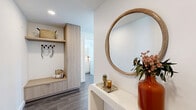 Located in the heart of San Diego's Columbia District, this thoughtfully designed two-bedroom, two-bathroom residence offers a seamless blend of modern architecture and urban living. The open-concept kitchen and living area serves as the centerpiece of the home, anchored by expansive floor-to-ceiling windows that flood the space with natural light and frame striking city skyline views. The kitchen features light wood cabinetry, a white tile backsplash, stainless steel appliances, and a large island with pendant lighting — ideal for both cooking and dining. The living area extends toward a private balcony accessible through sliding glass doors, offering an indoor-outdoor connection with panoramic views of downtown San Diego. The primary bedroom is generously sized, with large windows overlooking the cityscape, and connects to a spa-inspired en-suite bathroom complete with a glass-enclosed shower and a floating double vanity. The second bedroom also enjoys abundant natural light and city views. A second full bathroom features a soaking tub with tile surround. The entry hallway includes built-in storage cabinetry and coat hooks, providing functional organization. Dark hardwood-style flooring runs throughout, complementing the clean, neutral palette of the home.