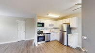 Located at 985 Grand Canyon Pkwy in Hoffman Estates, IL, this 2-bedroom, 1-bathroom unit offers a well-designed single-floor layout with a clean, neutral aesthetic throughout. The combined kitchen and living area serves as the heart of the home, featuring warm wood-look luxury vinyl flooring, a ceiling fan, and a thoughtfully updated kitchen outfitted with white shaker cabinetry, a mosaic tile backsplash, stainless steel appliances including a refrigerator, range, dishwasher, and built-in microwave, plus ample counter and storage space. The living area flows naturally from the kitchen, providing a comfortable and versatile space. The primary bedroom is generously sized, featuring the same wood-look flooring, multiple windows that invite natural light, and a wall-mounted HVAC unit. The second bedroom is finished with plush carpet, a window with outdoor views, a wall-mounted HVAC unit, and an accent wall with vertical shiplap-style paneling. Both bedrooms include closet storage. The bathroom is finished in crisp white subway tile, a soaking tub with shower, a modern vanity with an under-mount sink, and a mirrored medicine cabinet. The unit's neutral palette and updated finishes create a clean, move-in ready living environment.