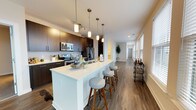 Located at 99 WestEdge St in Charleston, SC, this modern residence offers a thoughtfully designed open-concept layout with high-quality finishes throughout. The contemporary kitchen serves as the heart of the home, showcasing rich dark cabinetry, a large white quartz island with bar seating, stainless steel appliances including a French door refrigerator, and stylish pendant lighting. The kitchen flows seamlessly into the living area, which is bathed in natural light from expansive windows and features durable hardwood-style flooring. The bedrooms offer plush carpeting, ceiling fans, and generous windows that fill the rooms with daylight. Each bathroom is finished with dark wood vanities, white quartz countertops, framed mirrors, and walk-in glass shower enclosures, with direct access to spacious walk-in closets. A standout feature of this residence is the private outdoor terrace, finished with polished tile flooring and offering breathtaking panoramic views of the Charleston waterfront and surrounding cityscape — an ideal setting for outdoor relaxation. The overall ambiance is clean, contemporary, and refined, making this a compelling offering in one of Charleston's most desirable neighborhoods.